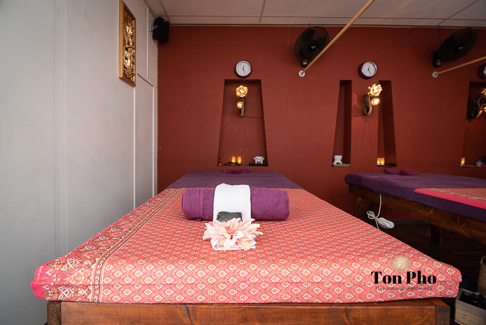 Behandelkamer met rode wanden en twee massagetafels