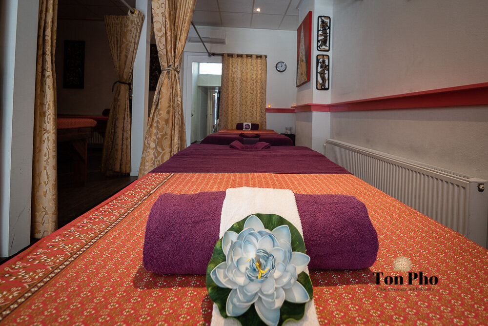 Massagetafel met Thaise stof, paarse handdoek en lotusbloem